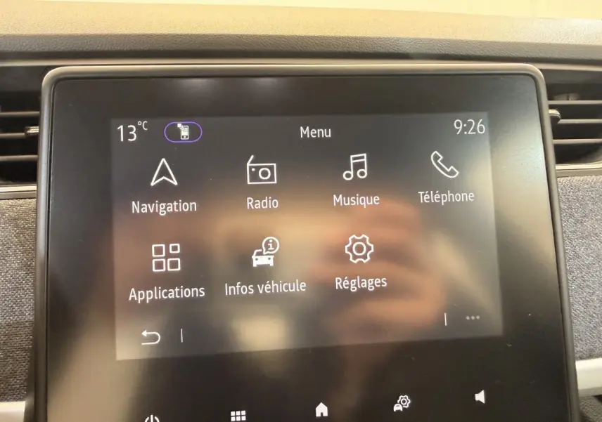 Écran tactile central de la Renault ZOE noire 2024 affichant le menu principal avec options navigation, radio et téléphone.