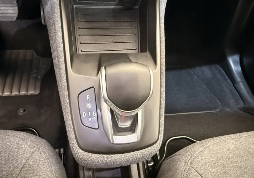 Gros plan sur la console centrale de la Renault ZOE noire 2024, montrant le levier de vitesses automatique et les sièges gris.