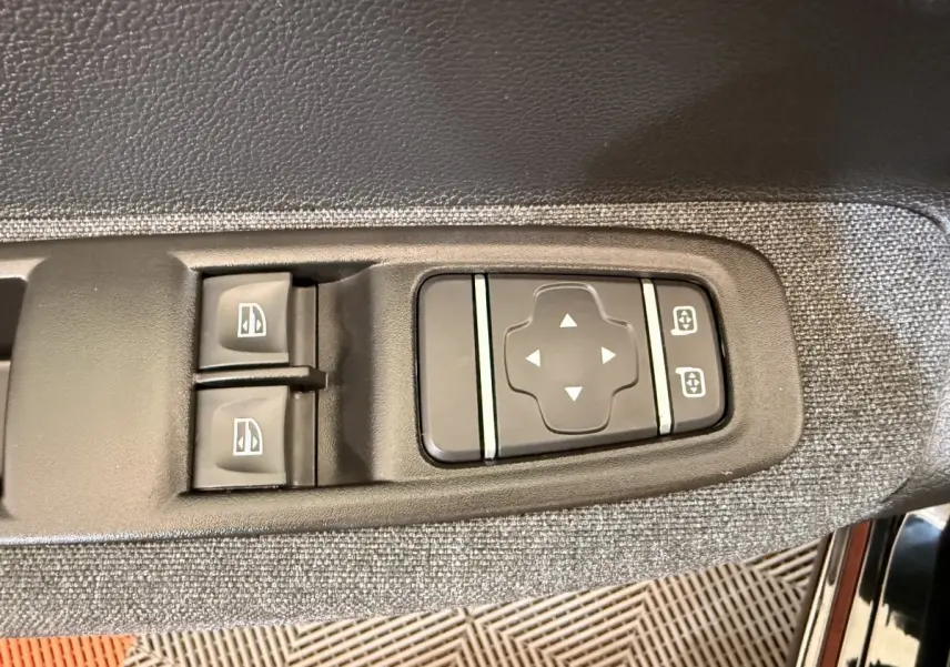 Gros plan sur les commandes de réglage des vitres et des rétroviseurs côté conducteur de la Renault ZOE noire 2024.