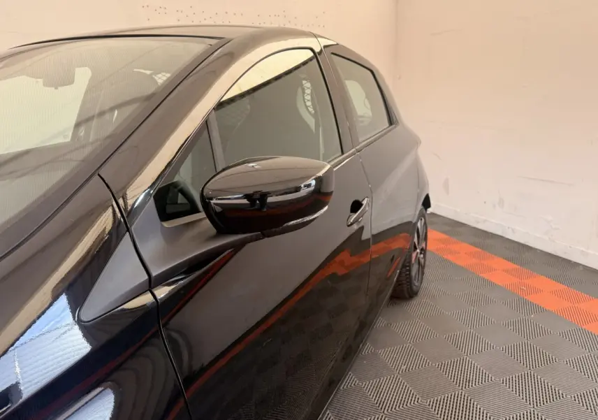 Vue de profil côté gauche sur une Renault ZOE noire électrique, mettant en valeur la portière et le rétroviseur.