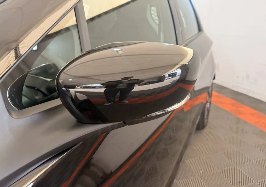 Rétroviseur côté conducteur noir brillant de la Renault ZOE 2024, vue rapprochée sur la portière avant.