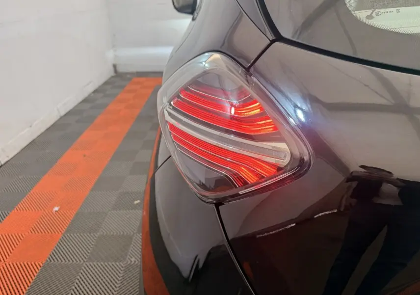 Gros plan sur le feu arrière gauche rouge et blanc d'une Renault ZOE noire, vue depuis l'arrière côté gauche.