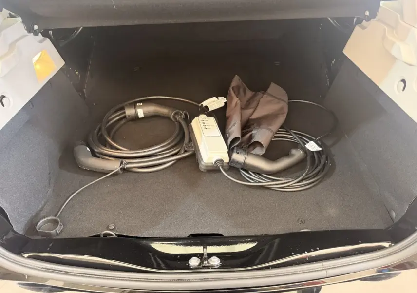 Coffre ouvert d'une Renault ZOE noire 2024 avec câble de charge électrique rangé à l'intérieur.