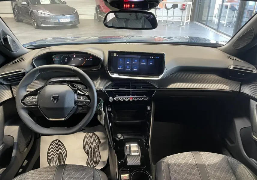 Vue intérieure avant du Peugeot 2008 bleu, tableau de bord avec écran tactile et volant compact cuir noir.