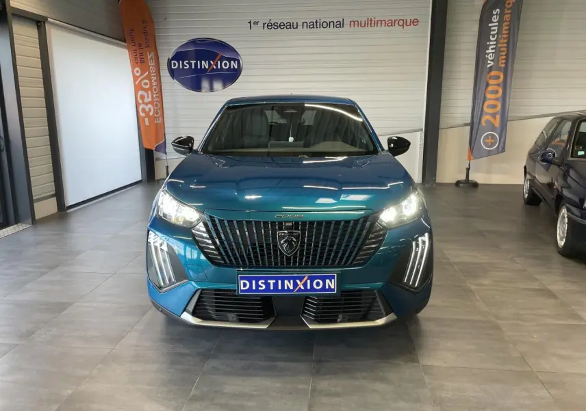 Vue frontale d'un Peugeot 2008 bleu métallisé avec calandre noire et feux LED allumés en showroom.