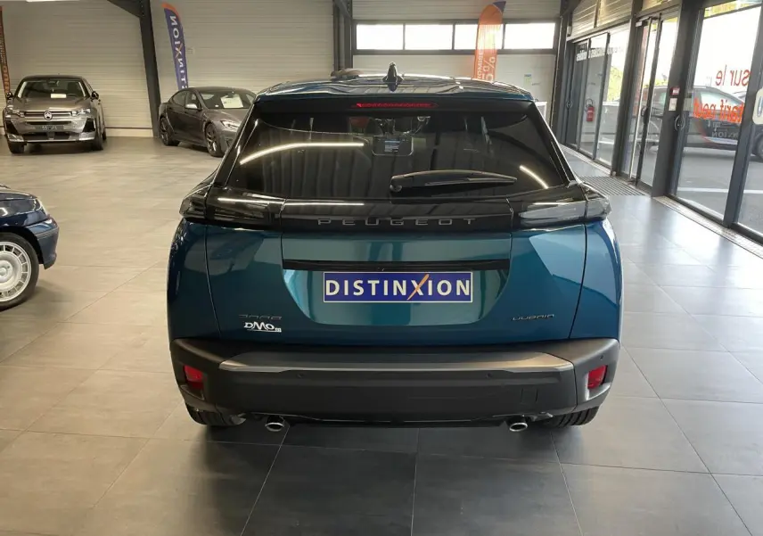Vue arrière d'un Peugeot 2008 bleu métallisé en showroom avec feux arrière à LED et double sortie d'échappement chromée.