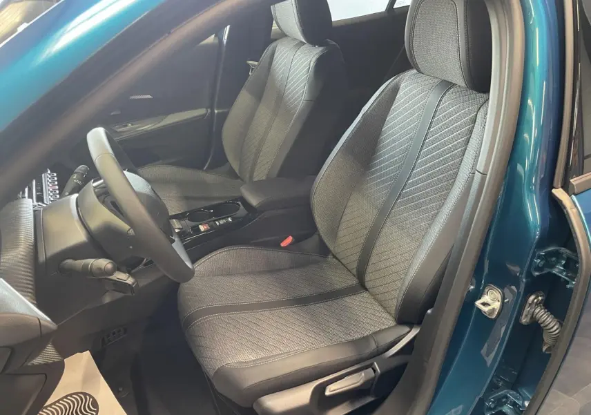 Vue intérieure côté conducteur du Peugeot 2008 bleu, mettant en valeur les sièges tissu et cuir avec surpiqûres Quartz.