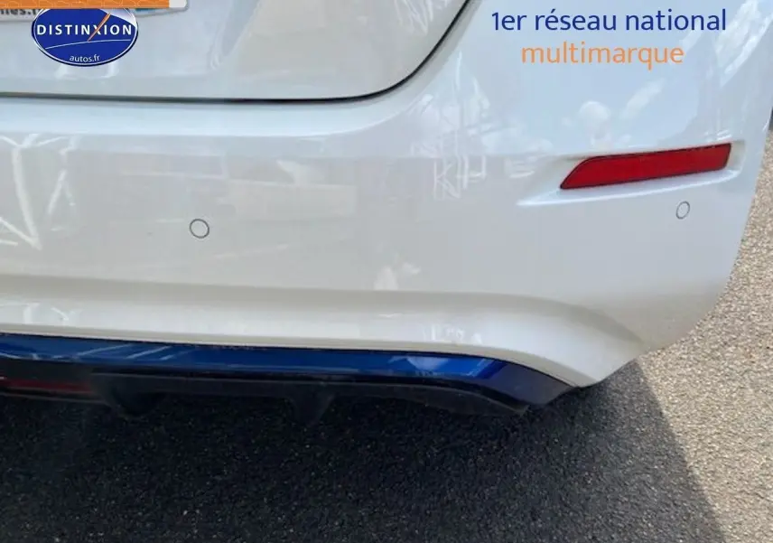 Gros plan sur le pare-chocs arrière blanc nacré d'une Nissan Leaf électrique 40kWh Acenta avec feux rouges et capteurs de recul visibles.