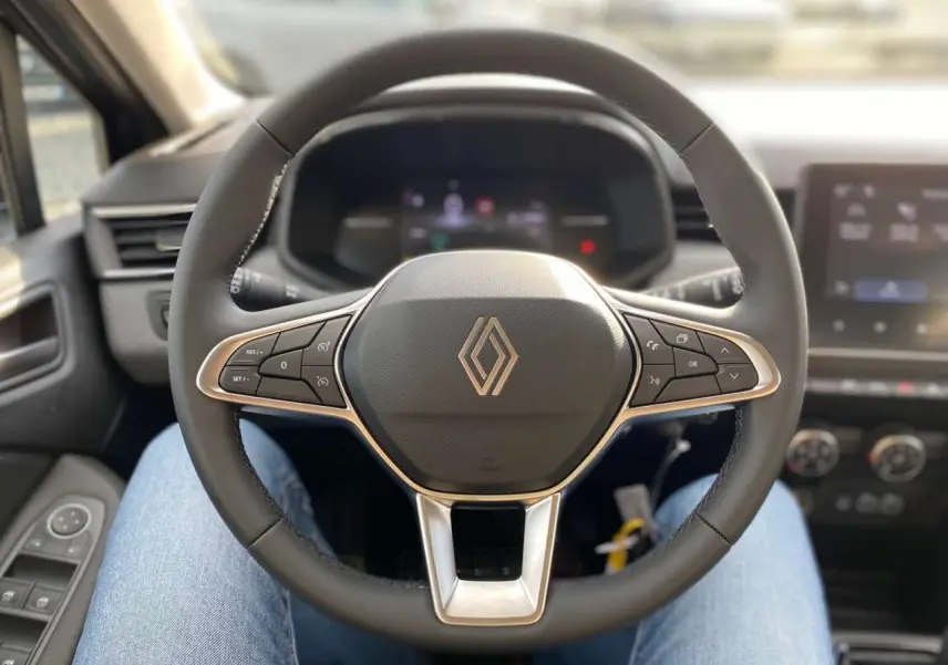 Vue centrée sur le volant noir de la Renault Clio 2025 avec commandes intégrées et tableau de bord numérique flou.