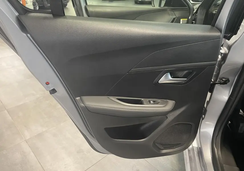 Vue rapprochée de la porte arrière droite gris Artense de la Peugeot 208 1.2i Hybrid Allure avec habillage noir et accoudoir gris.