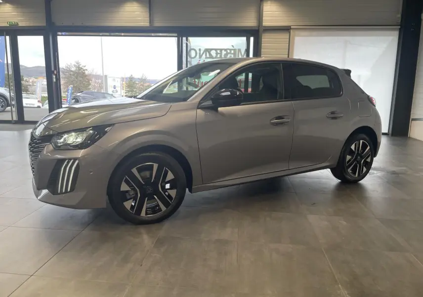 Peugeot 208 gris Artense vue de profil côté gauche en intérieur avec jantes alliage bi-tons et feux LED distinctifs.