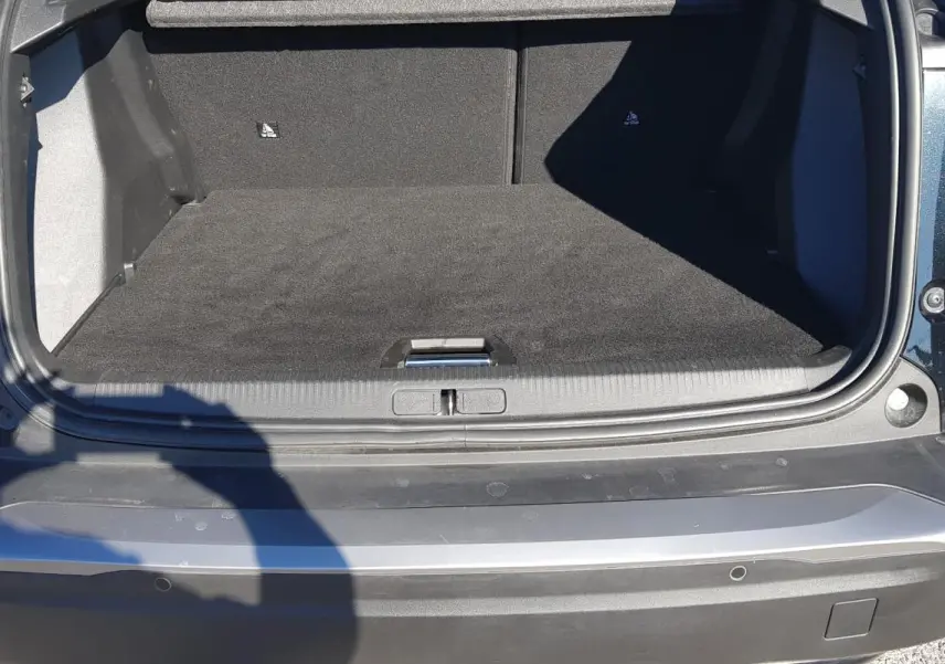 Coffre ouvert vu de l'arrière d'un Peugeot 2008 Hybrid 145 noir, montrant l'espace de chargement vide.