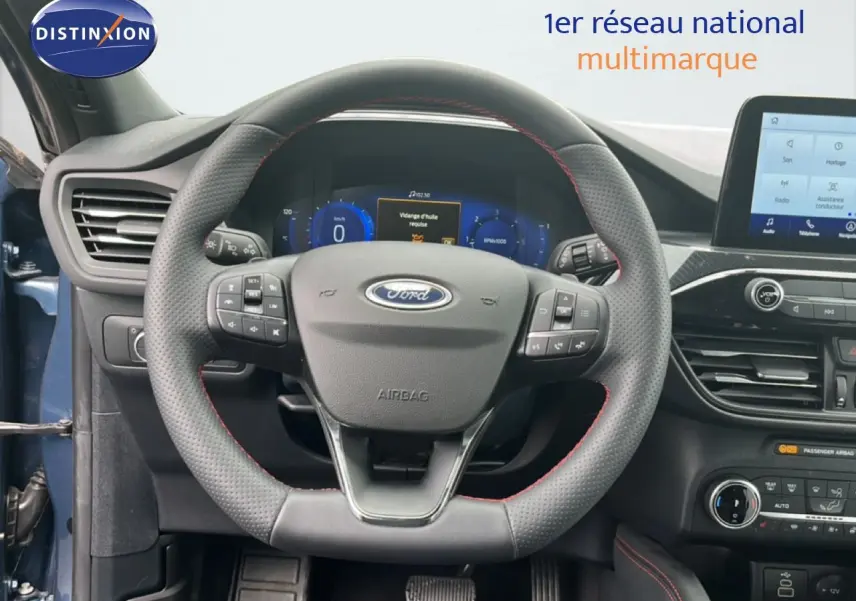 Vue intérieure centrée sur le volant en cuir noir avec surpiqûres rouges du Ford Kuga bleu chrome 2024, tableau de bord digital visible.