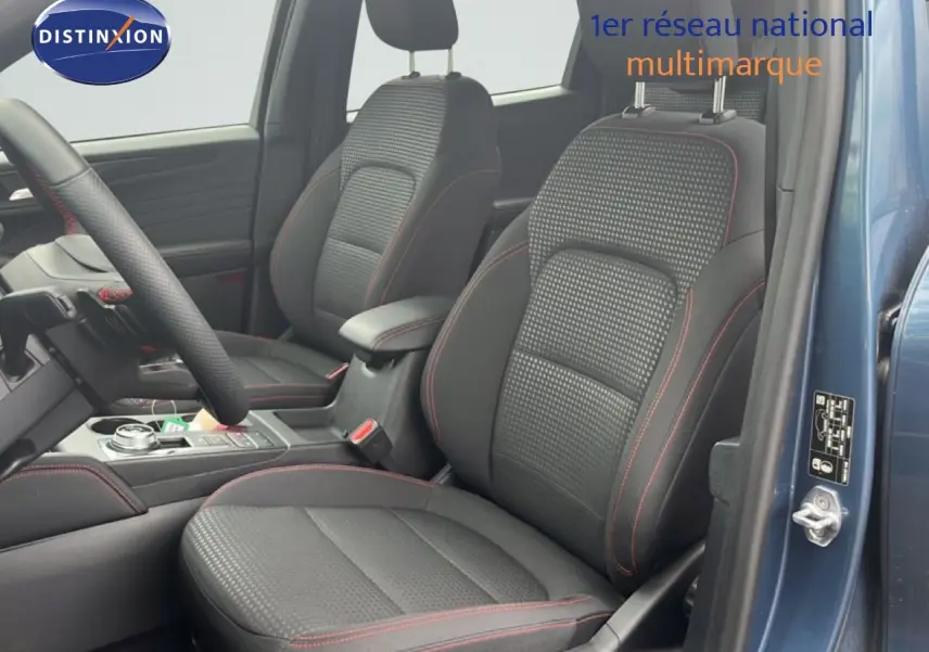 Vue intérieure côté conducteur du Ford Kuga bleu chrome métal 2024, sièges tissu noir avec surpiqûres rouges.