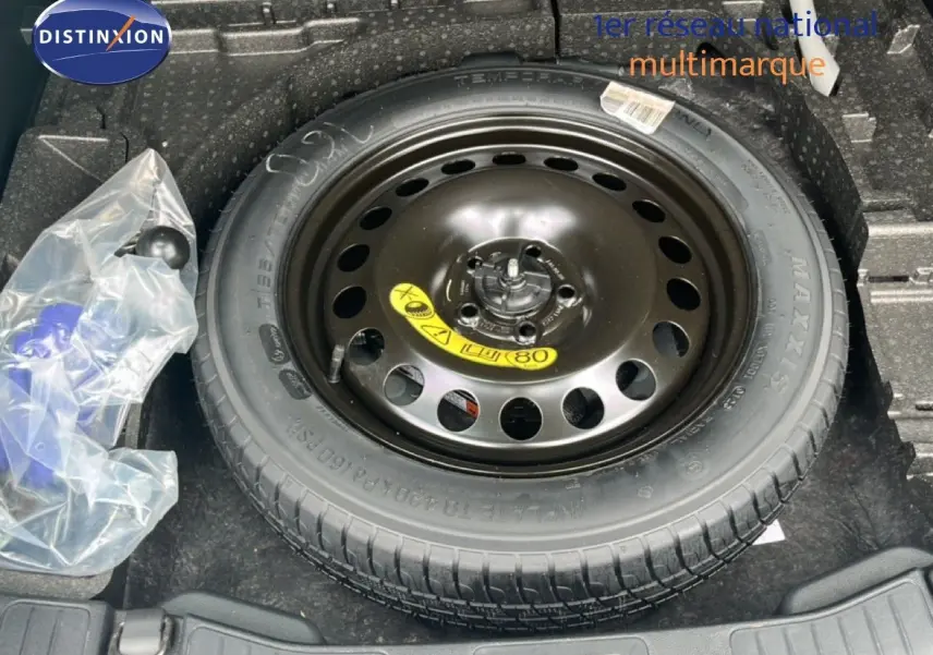 Vue plongeante sur la roue de secours noire dans le coffre d'un Ford Kuga bleu chrome 2024.