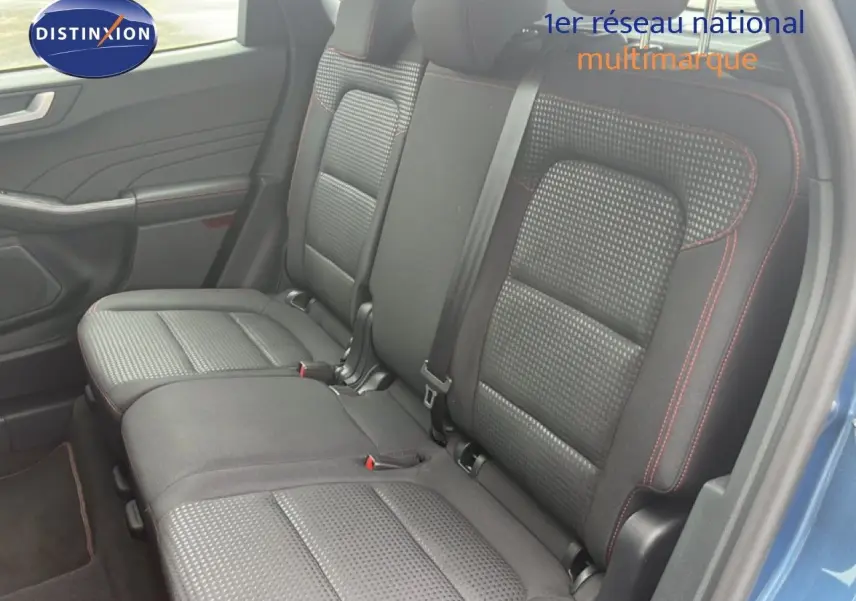 Vue intérieure du siège arrière droit du Ford Kuga 2024 bleu chrome, avec sellerie tissu noire et surpiqûres rouges.