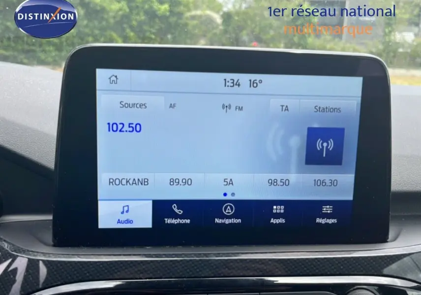 Écran tactile central du Ford Kuga bleu chrome 2024, affichant la radio FM avec interface moderne et commandes tactiles.