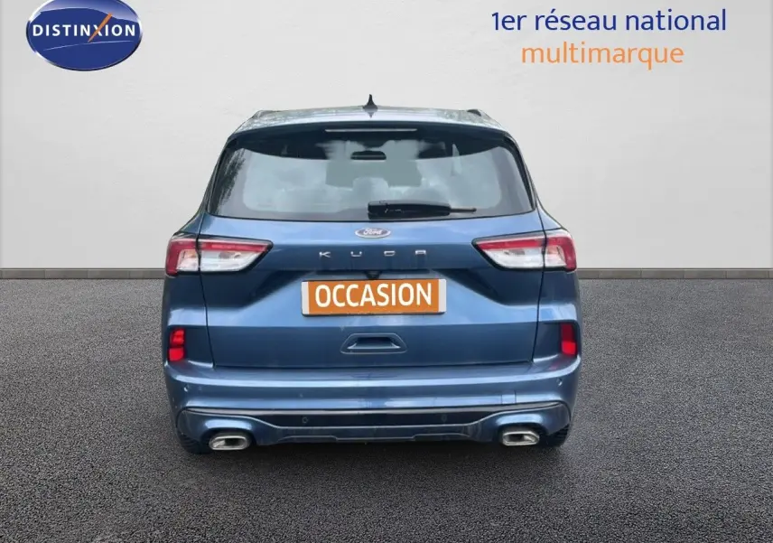 Vue arrière d'un Ford Kuga 2024 bleu chrome métal avec double sortie d'échappement et badge ST-LINE visible.