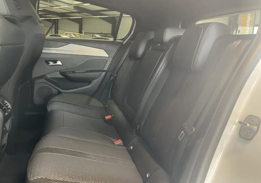 Vue intérieure côté droit sur la banquette arrière noire avec surpiqûres et porte blanc métallisé d'une Peugeot 308 GT 2025.