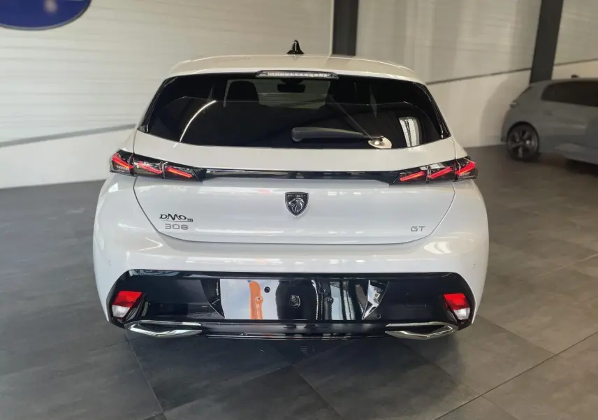 Vue arrière d'une Peugeot 308 GT blanche avec feux arrière à signature lumineuse et diffuseur noir brillant.