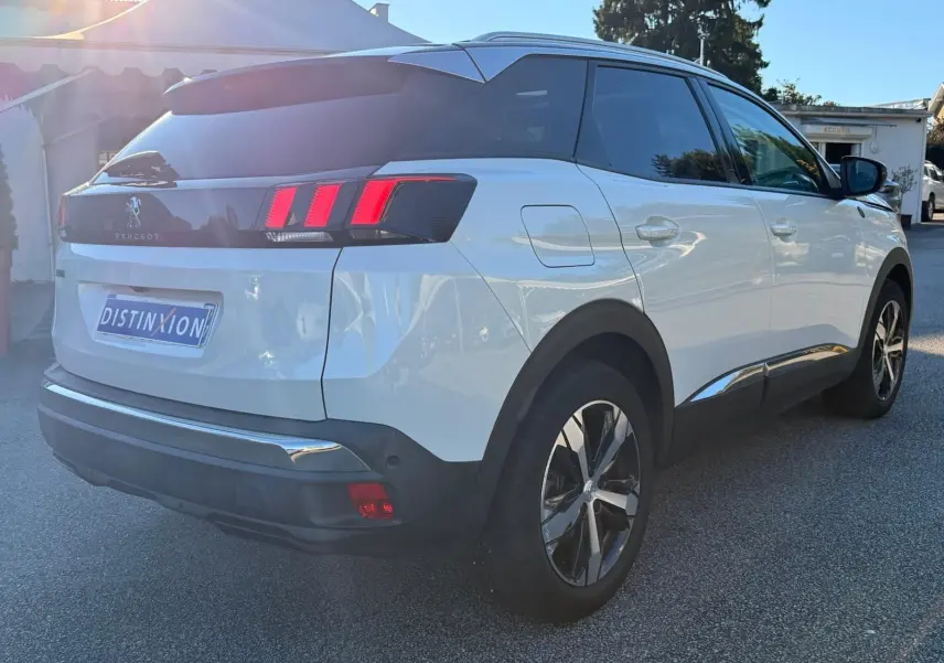 Peugeot 3008 blanc nacré vue 3/4 arrière côté gauche, avec toit noir et feux arrière à griffes rouges distinctifs.