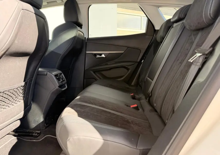 Vue latérale droite de l'intérieur arrière d'un Peugeot 3008 blanc nacré, sièges en cuir et alcantara noirs.