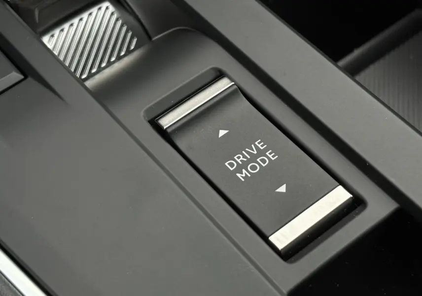 Gros plan sur le bouton Drive Mode noir et argenté de la console centrale du Citroën C5 Aircross Hybrid 2025.