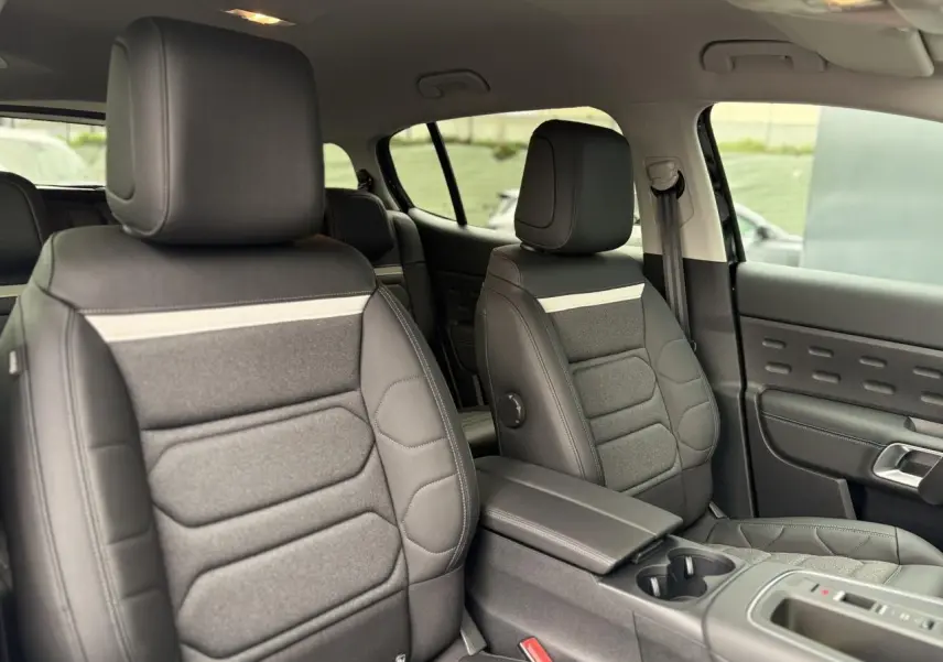 Vue intérieure côté droit des sièges avant en tissu et cuir noir avec accoudoir central du Citroën C5 Aircross Hybrid 2025.