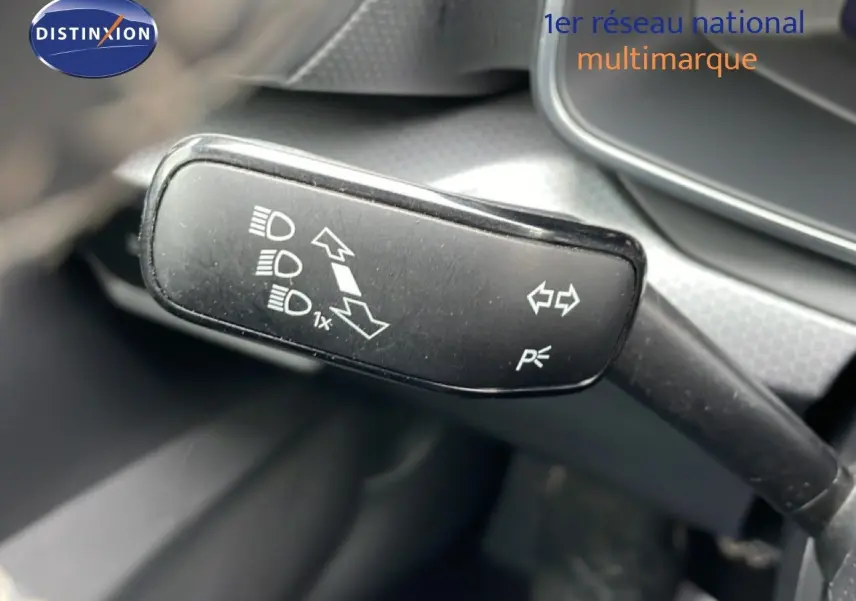 Gros plan sur la commande de clignotants et feux du SEAT Leon 2025, intérieur gris et noir visible en arrière-plan.