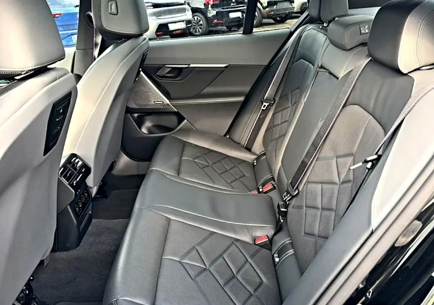 Vue intérieure côté droit des sièges arrière en cuir noir avec surpiqûres et accoudoir central de la BMW Série 5 i5 M60 2024.