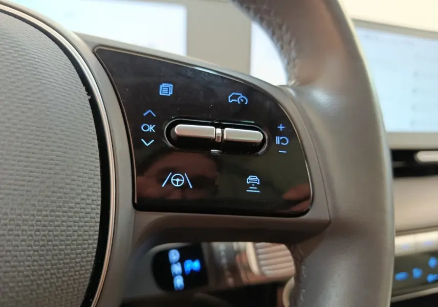Gros plan sur les commandes au volant cuir beige du Hyundai IONIQ BEV 77KWH AWD Executive 2023.