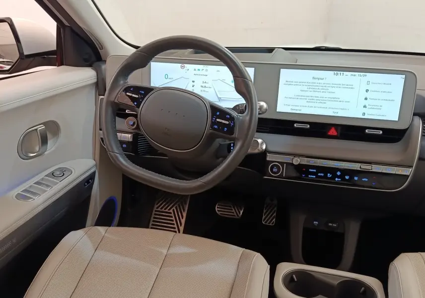 Vue intérieure côté conducteur du tableau de bord beige de la Hyundai IONIQ BEV 77KWH AWD Executive 2023 avec écran tactile large.