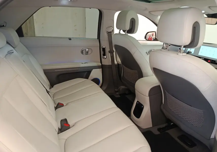 Vue intérieure côté gauche montrant la banquette arrière beige et les dossiers des sièges avant du Hyundai IONIQ BEV 2023.