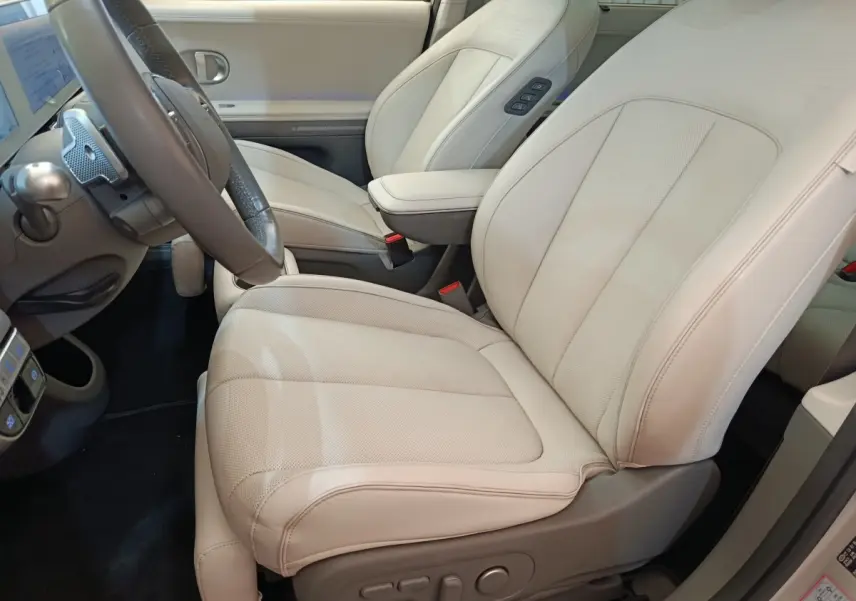 Vue intérieure côté conducteur du siège avant beige clair en cuir du Hyundai IONIQ BEV 77KWH AWD Executive 2023.