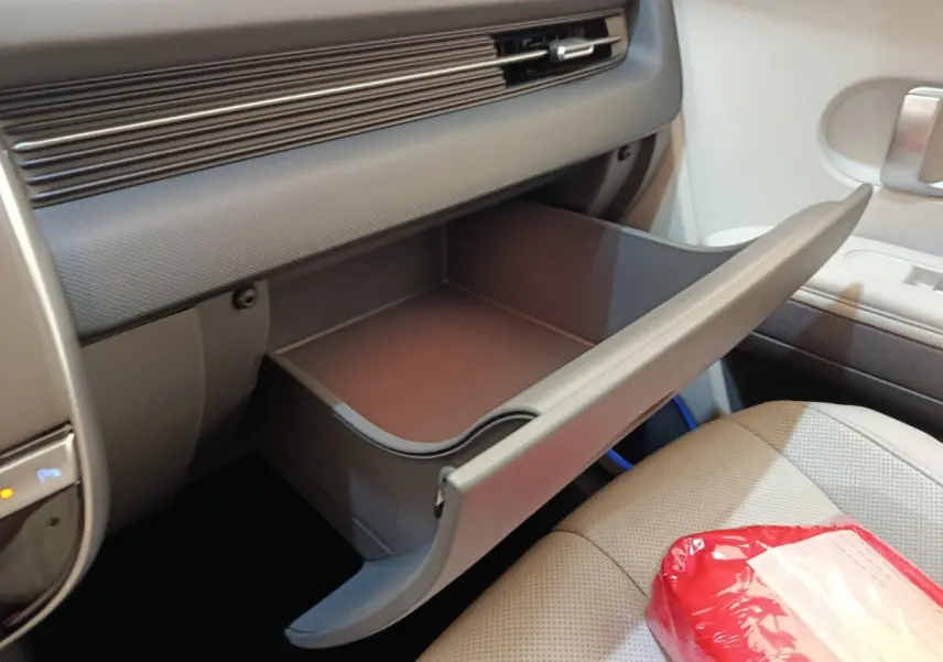 Intérieur de la Hyundai IONIQ BEV 77KWH AWD Executive 2023, vue de la boîte à gants ouverte côté passager beige.