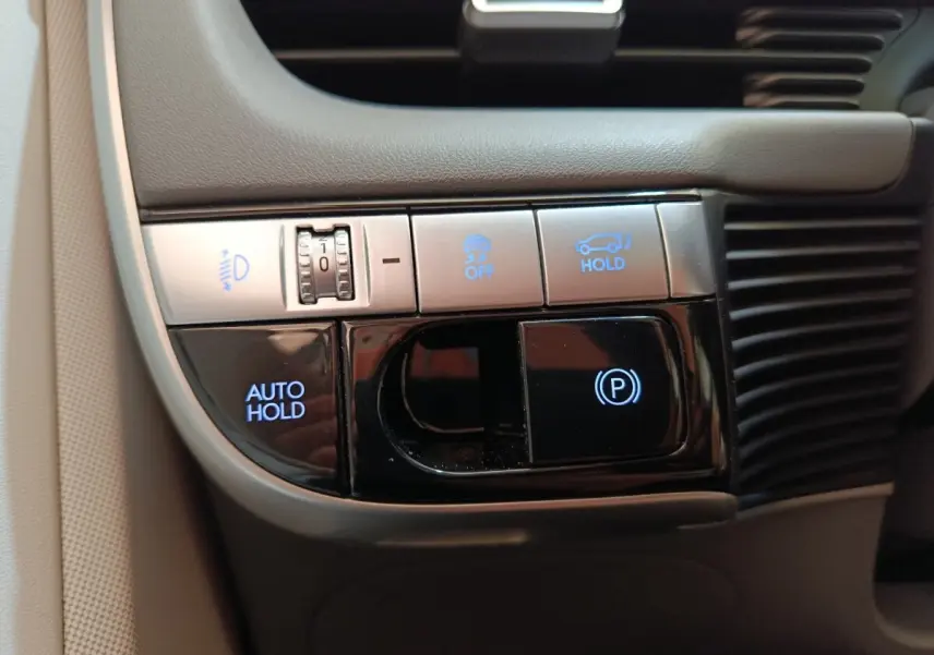 Gros plan sur les commandes de maintien automatique et frein de stationnement du Hyundai IONIQ beige 2023.