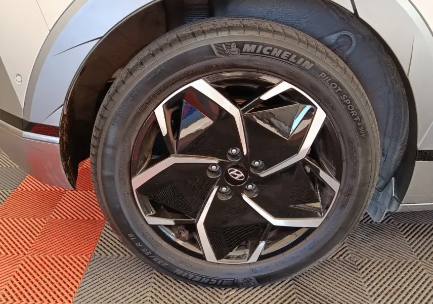 Gros plan sur la roue avant droite avec jante noire et argentée du Hyundai IONIQ beige 2023 électrique.