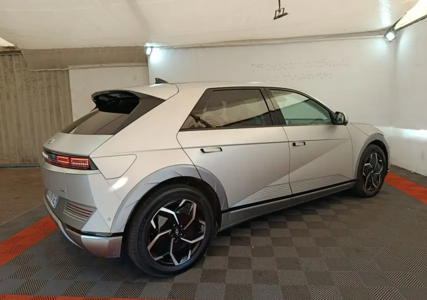 Vue 3/4 arrière droite d'une Hyundai IONIQ 5 beige électrique, avec feux arrière LED et jantes noires distinctives.