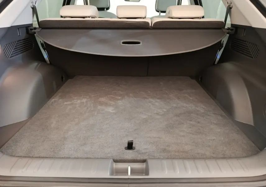 Coffre ouvert vu de l'arrière d'une Hyundai IONIQ beige 2023, avec banquette arrière et cache-bagages déployé.