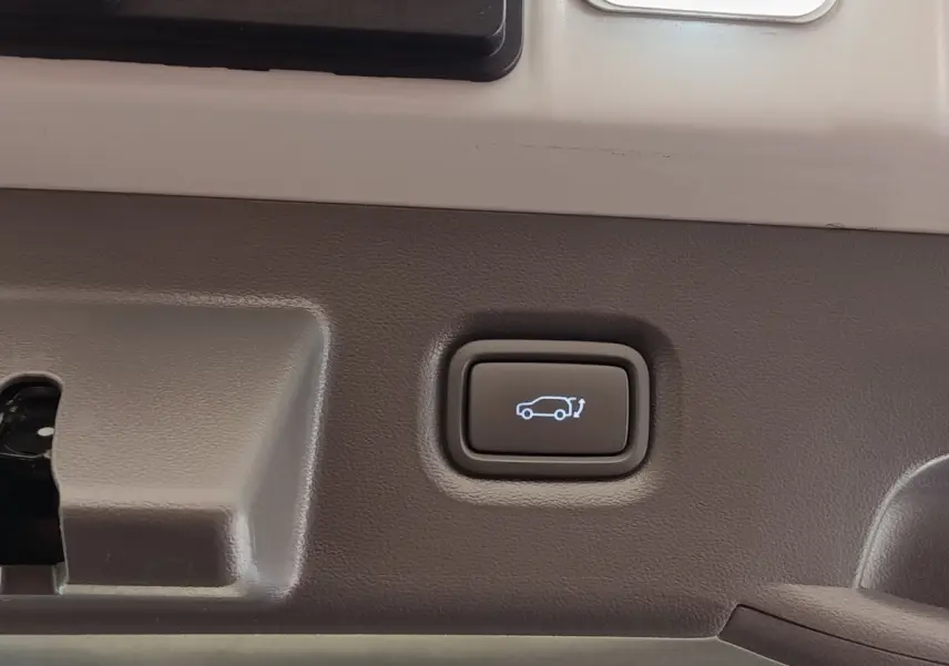 Bouton d'ouverture électrique du coffre sur la garniture intérieure beige d'une Hyundai IONIQ BEV 77KWH AWD Executive 2023.