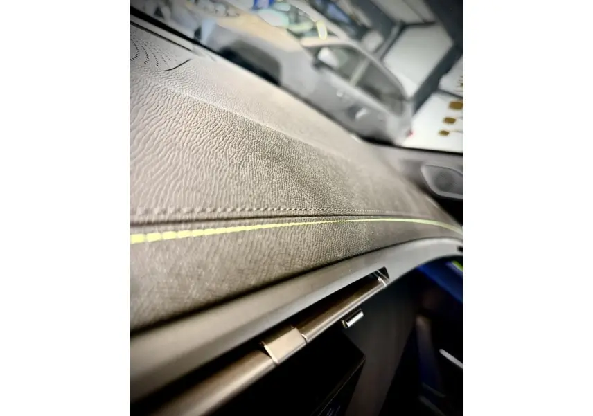 Gros plan sur la planche de bord texturée avec surpiqûres vertes de la Peugeot 308 GT 2025 gris selenium.