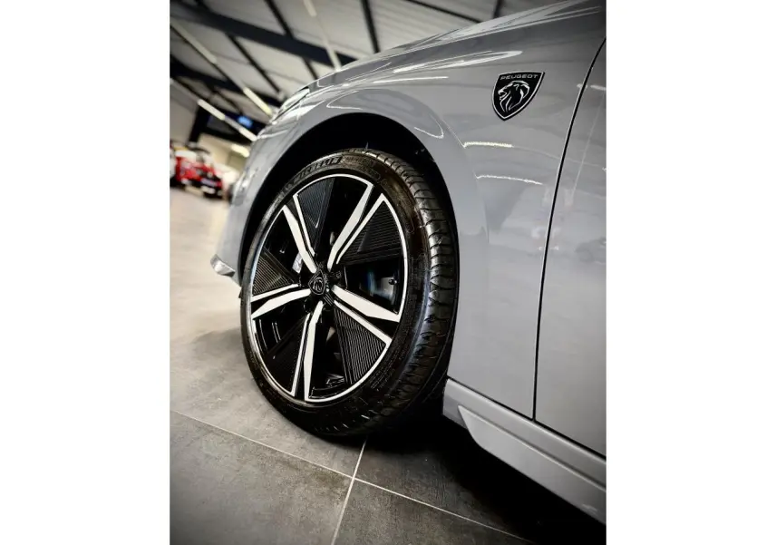Gros plan sur la roue avant gauche et l'aile gris sélénium d'une Peugeot 308 GT avec logo lion noir brillant.