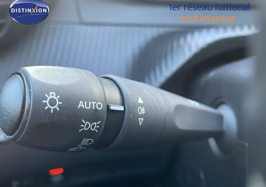 Gros plan sur la commande des phares d'une Peugeot 208 électrique gris Artense, intérieur côté gauche.