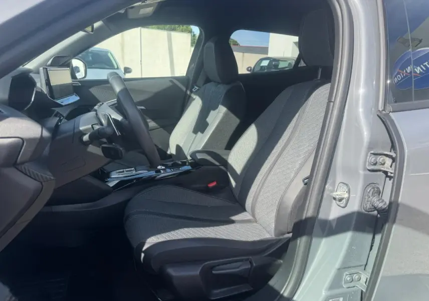 Intérieur de la Peugeot 2008 Hybrid gris, vue côté conducteur ouverte, sièges tissu gris et tableau de bord moderne.