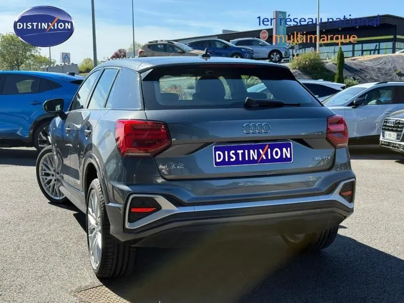 Audi Q2 35 TDI S line gris Daytona nacré, vue 3/4 arrière mettant en valeur ses feux et lignes dynamiques.