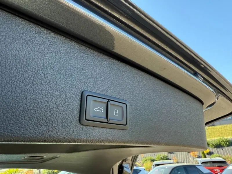 Gros plan sur les boutons d'ouverture et de verrouillage du coffre du toit arrière d'un Audi Q2 35 TDI gris Daytona nacré.