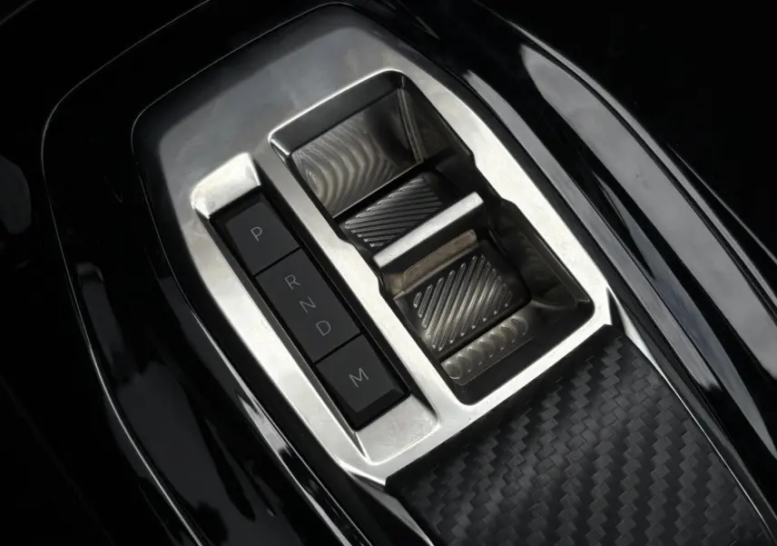 Gros plan sur le sélecteur de vitesses automatique en aluminium et noir dans la console centrale d'une Peugeot 208 Hybrid 110 e-DSC6 GT.
