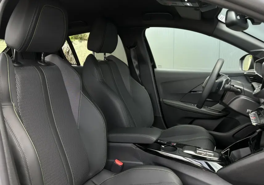 Vue intérieure côté conducteur de la Peugeot 208 Hybrid 110 e-DSC6 GT avec sellerie noire et surpiqûres vertes Adamite.