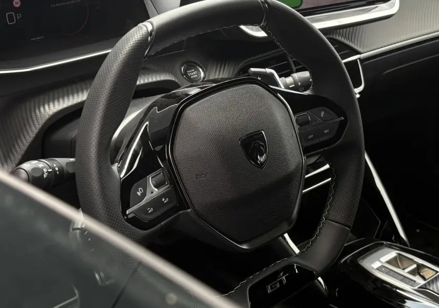 Vue rapprochée du volant compact cuir noir avec badge GT et commandes intégrées du Peugeot 208 Hybrid 110 e-DSC6.