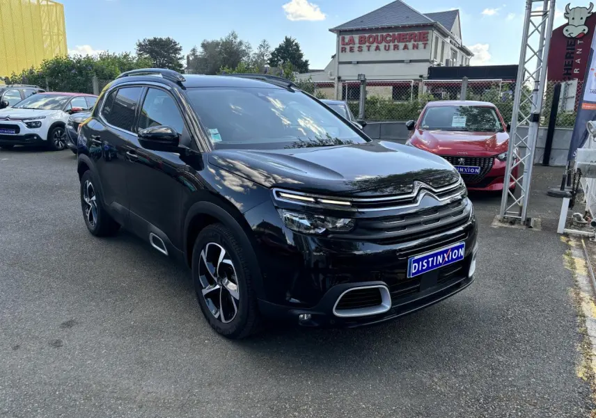 Citroën C5 Aircross noir métallisé en 3/4 avant droit, avec calandre distinctive et jantes bicolores visibles.